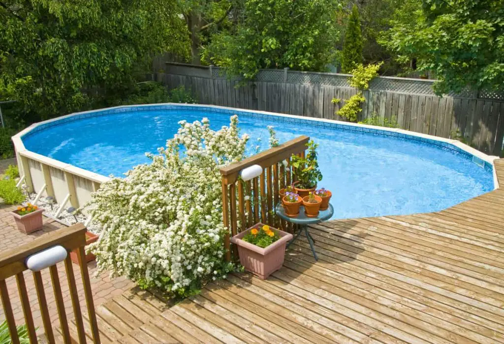 Above ground pool with a deck in a beautiful backyard.