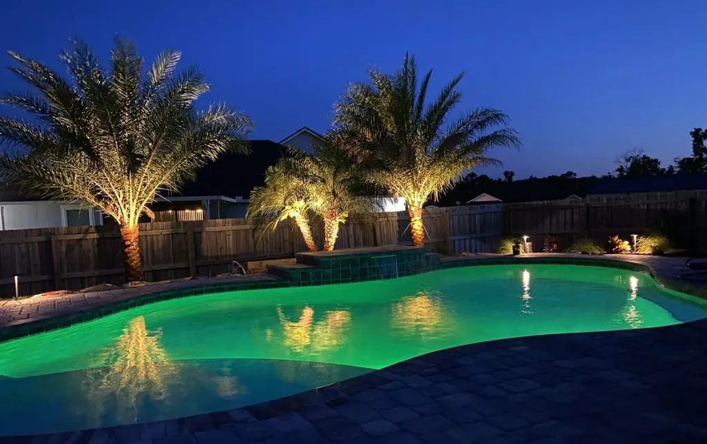 Pool at night with lighting and landscaping.