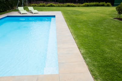 Small splashes of pool water onto grass will likely not damage it.