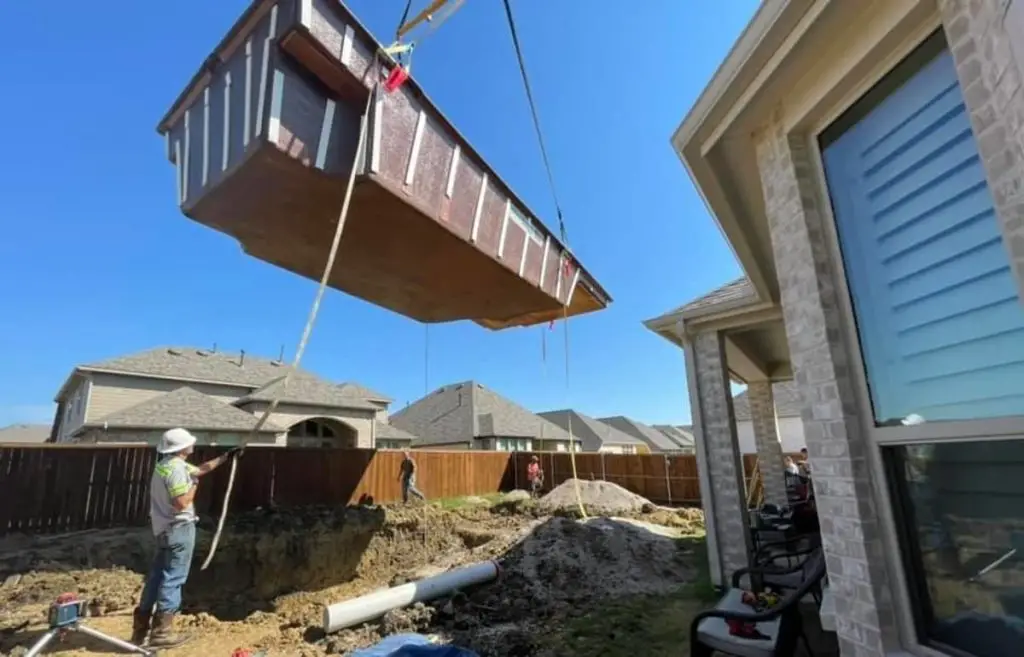 Fiberglass pools are inserted into the in-ground hole by the use of a crane.