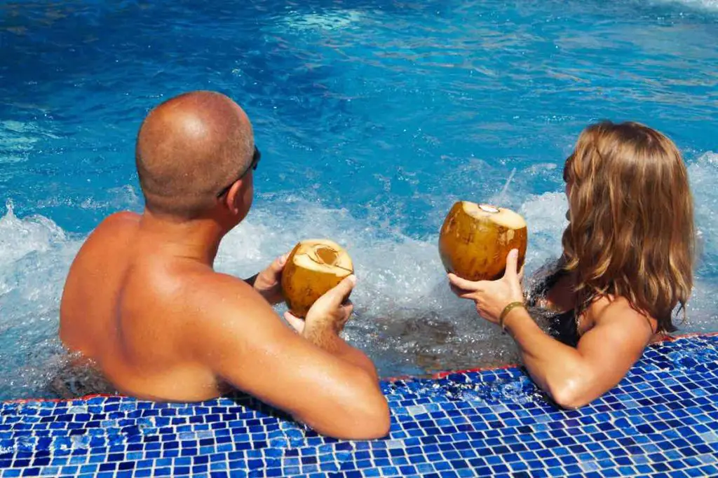 Couple with coconut drink relaxing in hot tub.