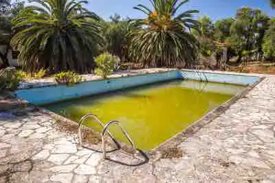 A dirty green swimming pool in an abandoned holiday complex in Greece.
