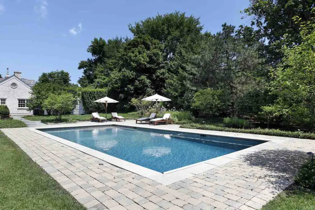 Swimming pool of luxury home with deck chairs